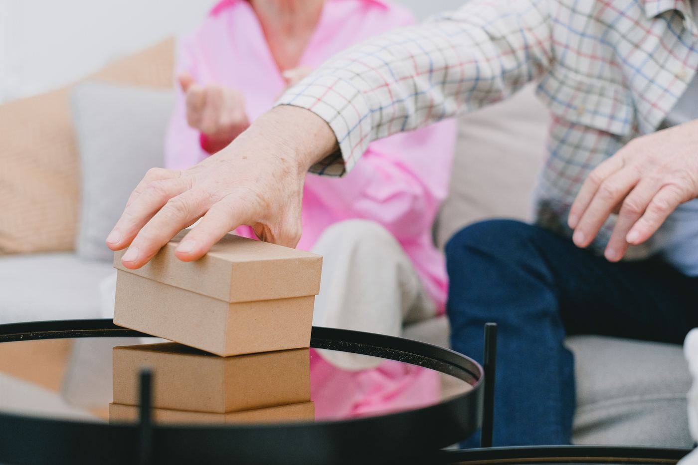 Close-up of an older adult's hands packing a small keepsake box while downsizing