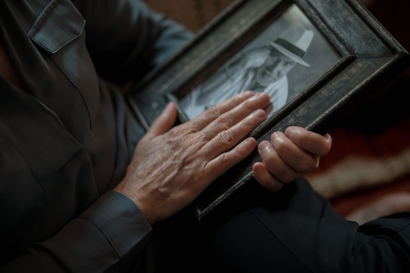 Hand resting gently on a framed vintage family photograph, representing settling a long-held family home in Newhall