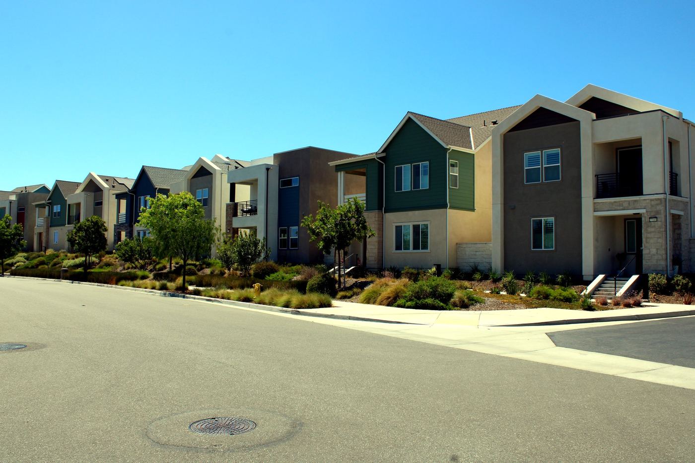 Row of newer two-story homes on a quiet Valencia, Santa Clarita street in late-summer light