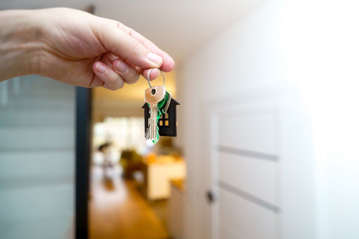 Hand holding new house keys inside a home entryway, Santa Clarita buyer