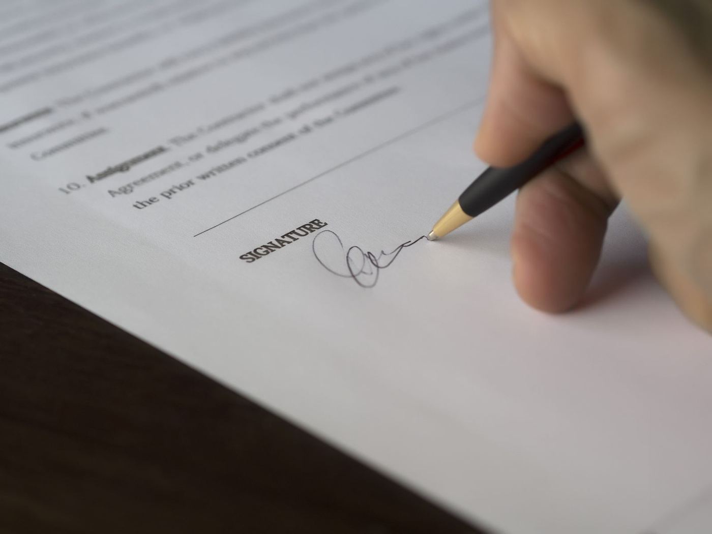 Hand signing closing documents, representing what happens during escrow when selling a home in Santa Clarita