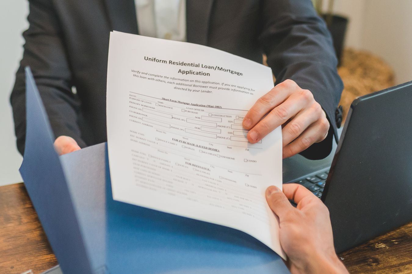 Hands exchanging a mortgage application document, representing a Valencia home buyer getting financing ready